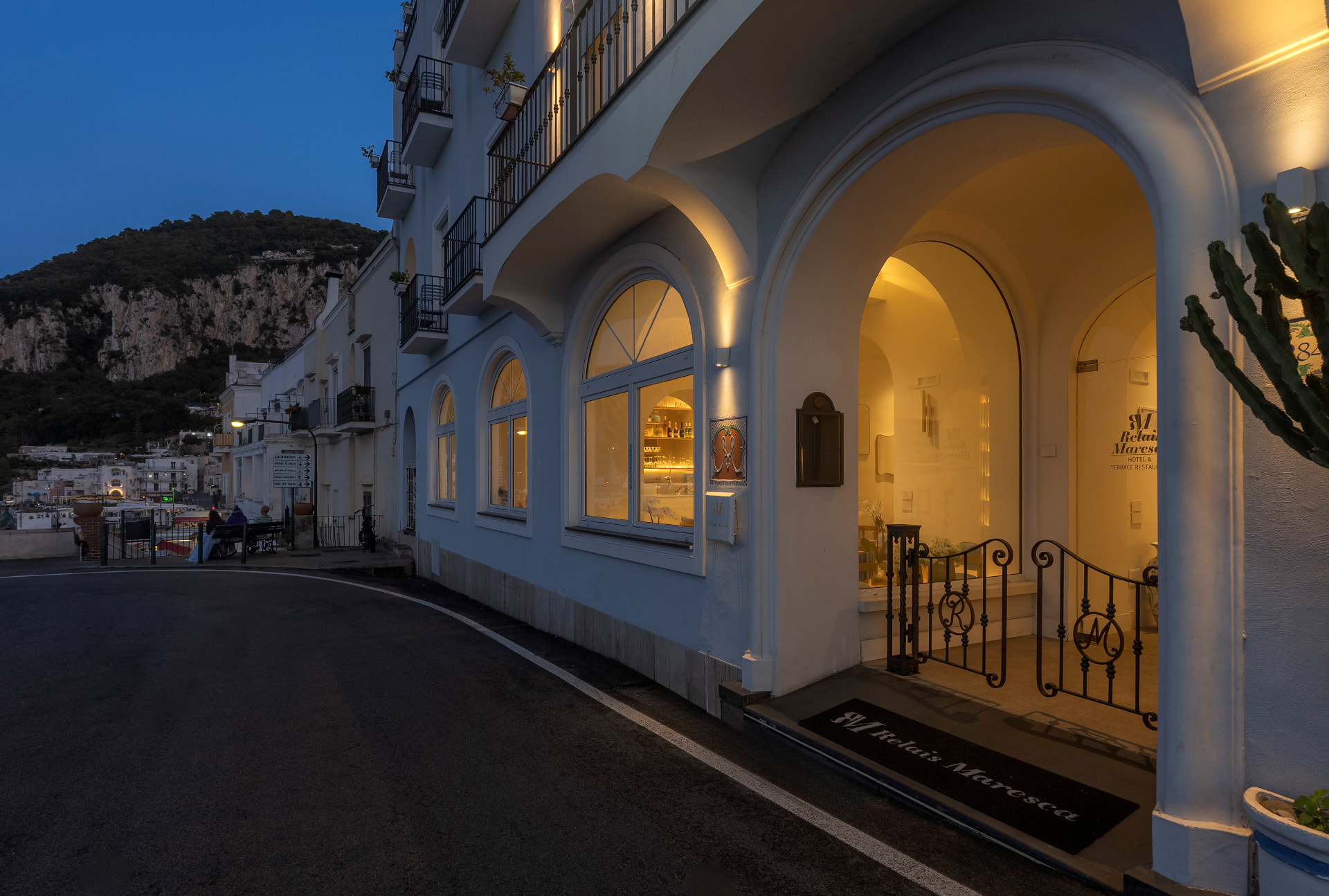 L'ingresso illuminato di Relais Maresca su Via Marina Grande al tramonto